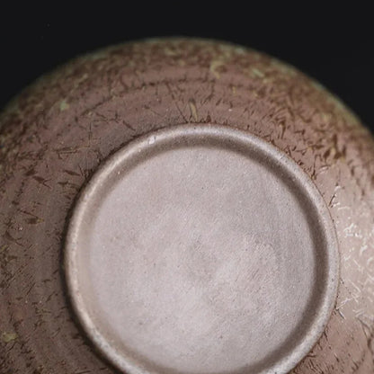 Vue du dessous d’une théière japonaise en céramique montrant la base brute et texturée.