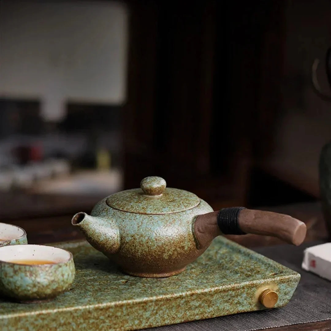 Théière japonaise en céramique émaillée vert céladon, posée sur un plateau assorti avec tasses à thé.