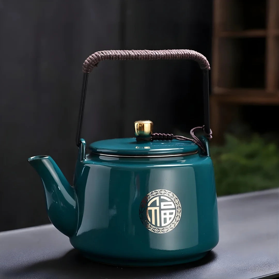 Théière japonaise en métal vert émaillé avec motif circulaire décoratif, présentée sur une table.