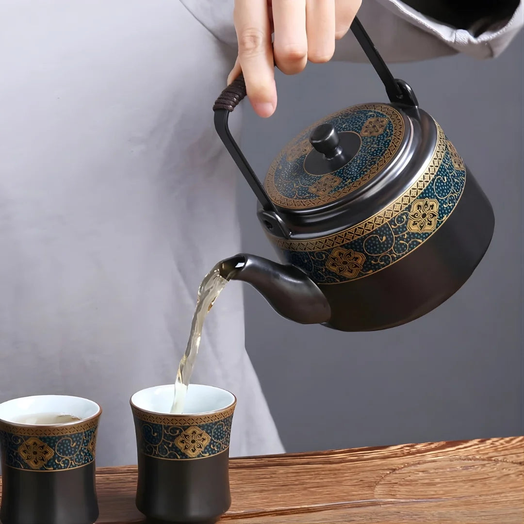 Service du thé : théière japonaise en métal décorée versant le thé dans deux tasses assorties.