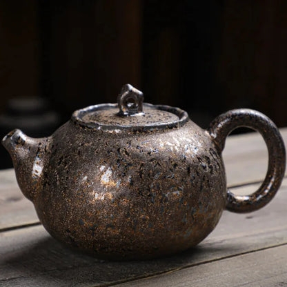 Théière japonaise artisanale en céramique à glaçure brun foncé texturée, posée sur une surface en bois.