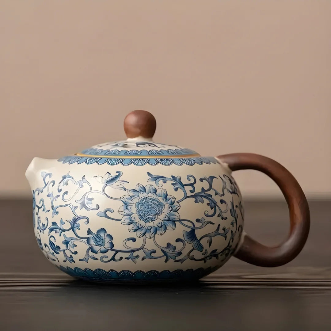 Théière japonaise en céramique vue de profil, décor floral bleu sur fond blanc, avec poignée latérale en bois.