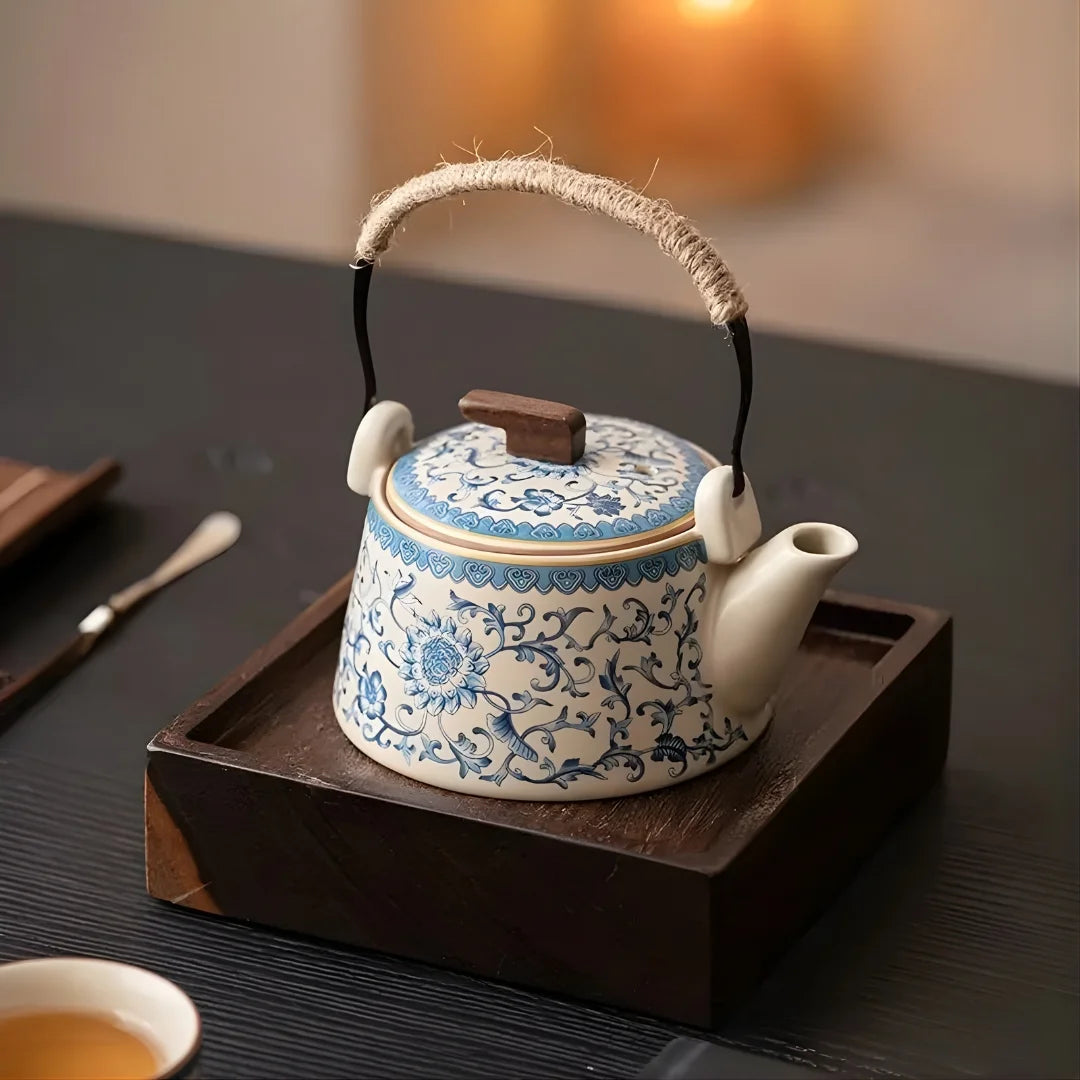 Théière japonaise en céramique décorée bleu et blanc, posée sur un plateau en bois, ambiance lumineuse et chaleureuse.