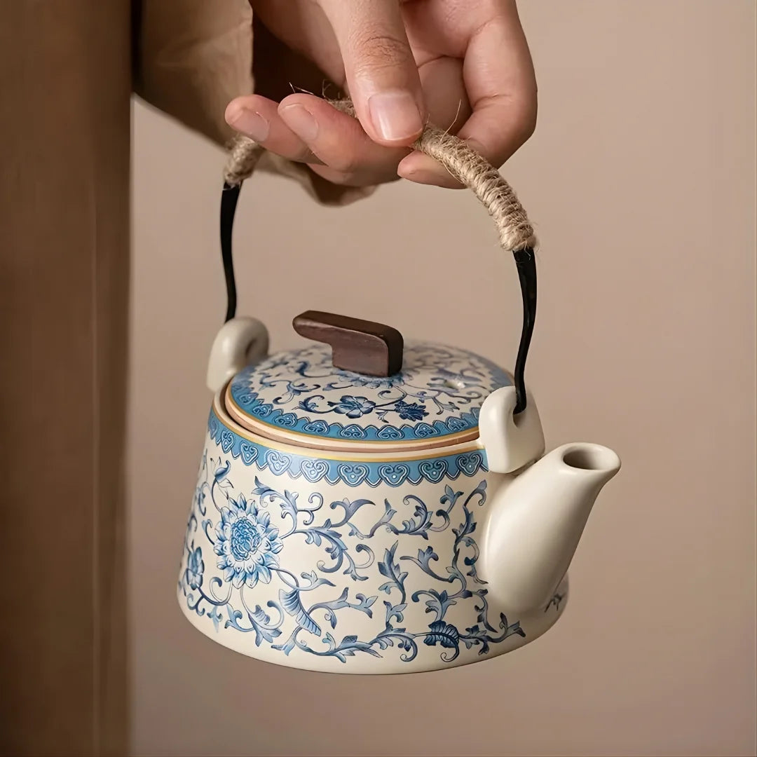 Théière japonaise en céramique décorée, tenue par l’anse en corde, montrant le bec verseur et le couvercle.