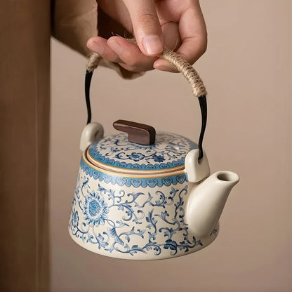 Théière japonaise en céramique décorée, tenue par l’anse en corde, montrant le bec verseur et le couvercle.