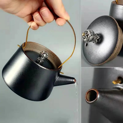 Main versant le thé depuis une théière en céramique noire mate avec anse en laiton.