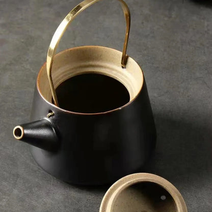 Théière en céramique noire ouverte, montrant l’intérieur et le couvercle posé à côté.