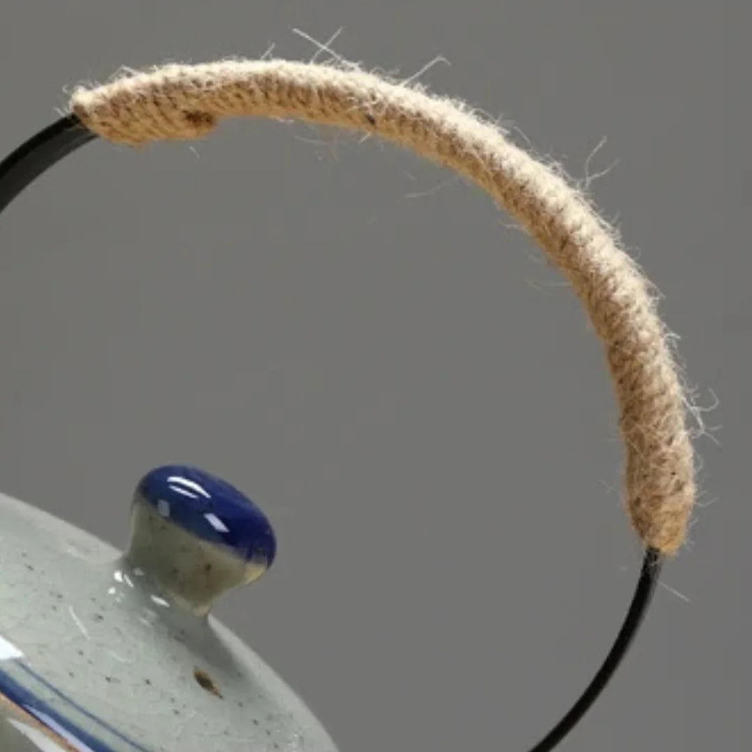 Gros plan sur l’anse en métal gainée de corde naturelle d’une théière japonaise en céramique.
