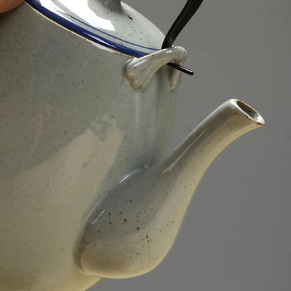 Détail du bec verseur d’une théière japonaise en céramique émaillée gris clair.