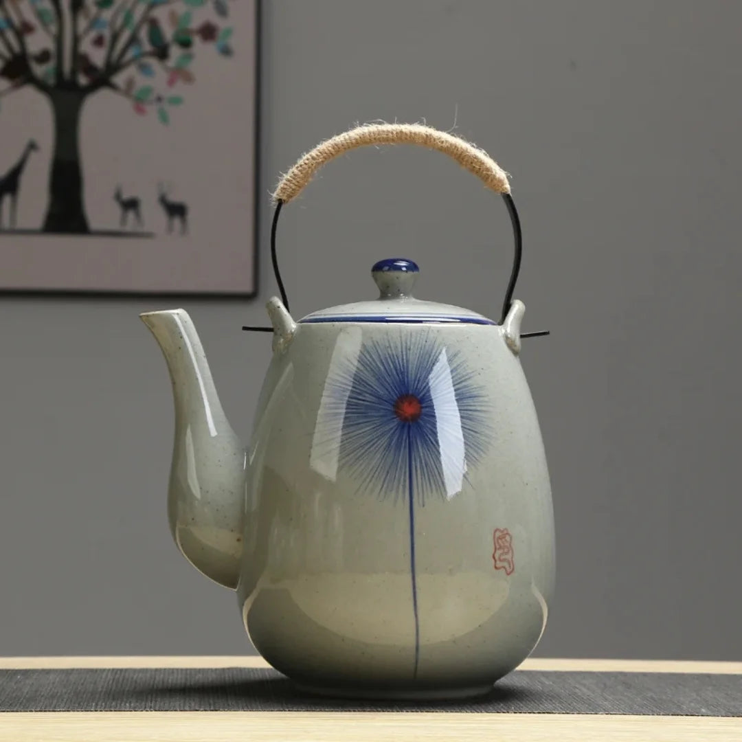 Théière japonaise en céramique décorée d’un motif floral bleu central, présentée de face.