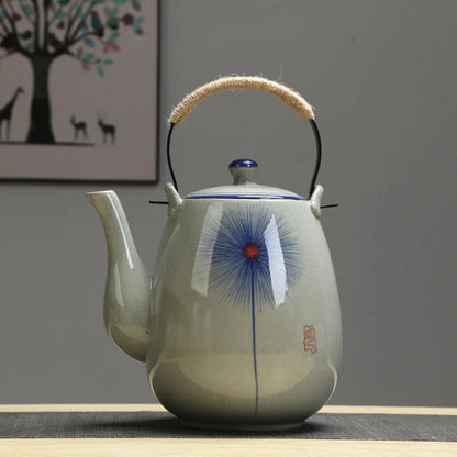 Théière japonaise en céramique décorée d’un motif floral bleu central, présentée de face.