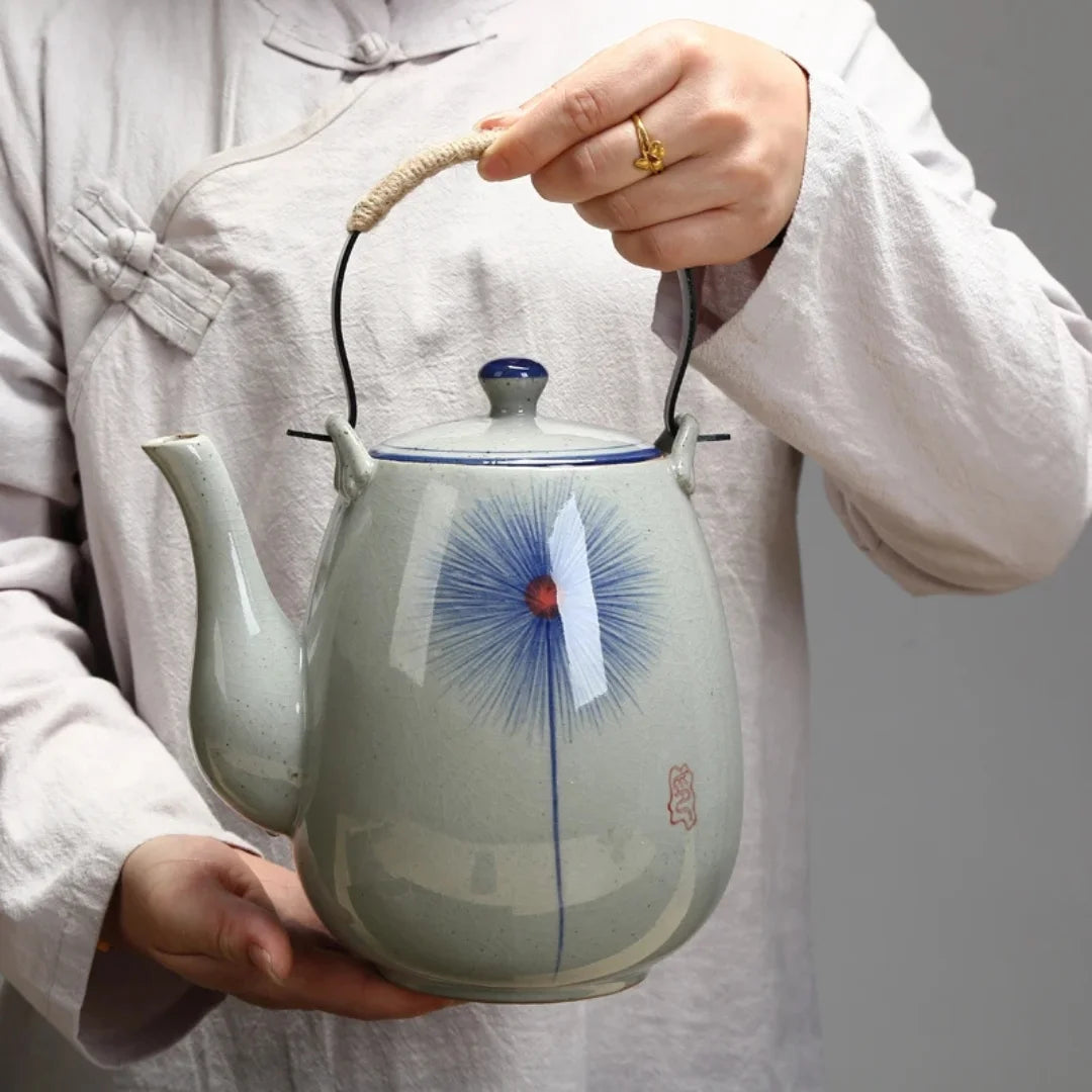 Personne tenant une théière japonaise en céramique décorée, montrant l’échelle et la prise en main.