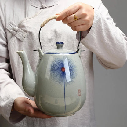 Personne tenant une théière japonaise en céramique décorée, montrant l’échelle et la prise en main.