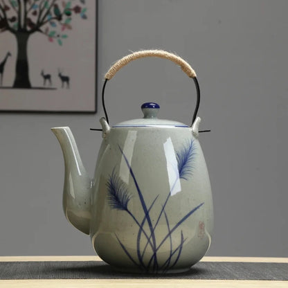 Théière japonaise en céramique émaillée gris clair, décor peint bleu inspiré de graminées, avec anse gainée de corde.