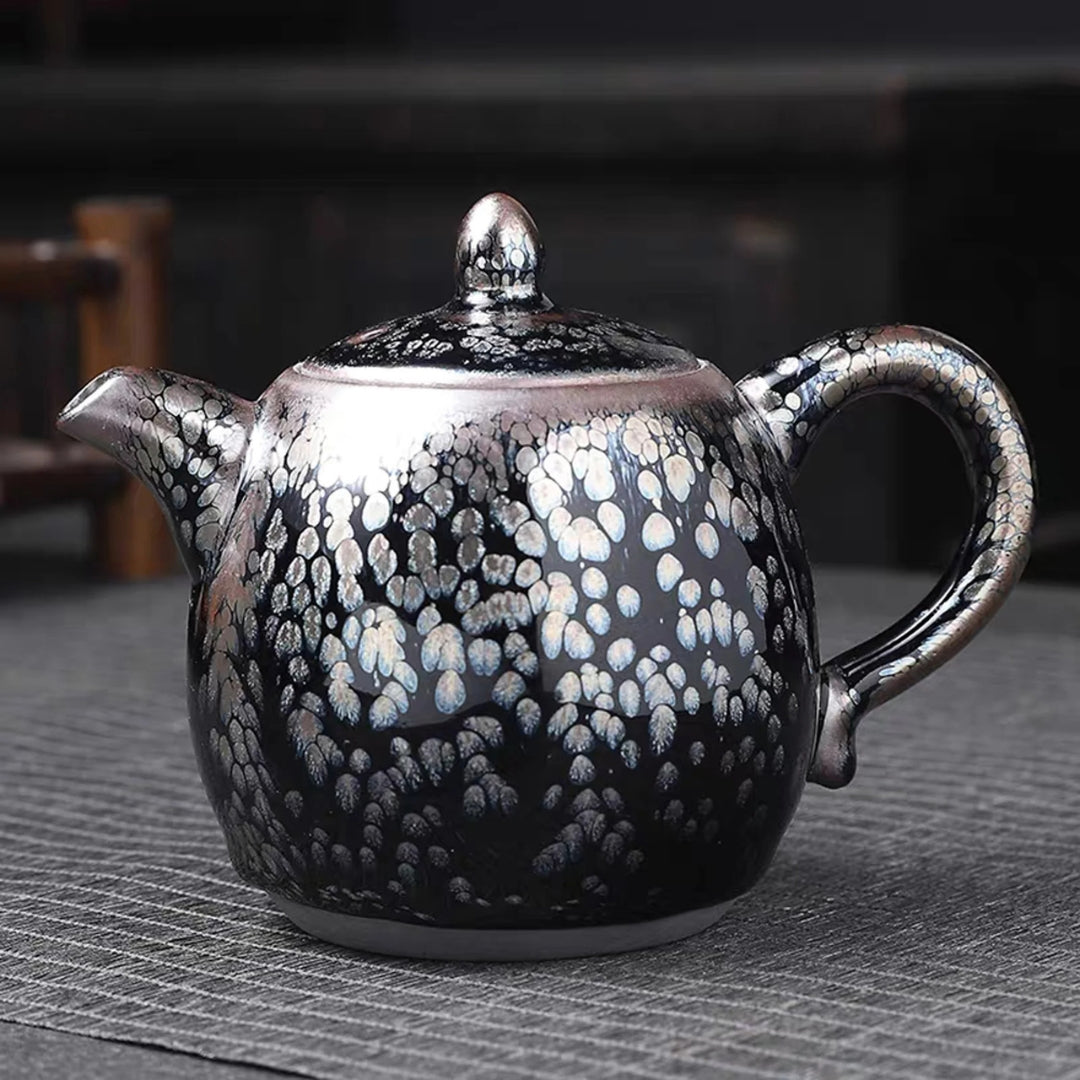 Théière japonaise artisanale à glaçure cristallisée noire, avec bec verseur court, couvercle et anse arrondie.