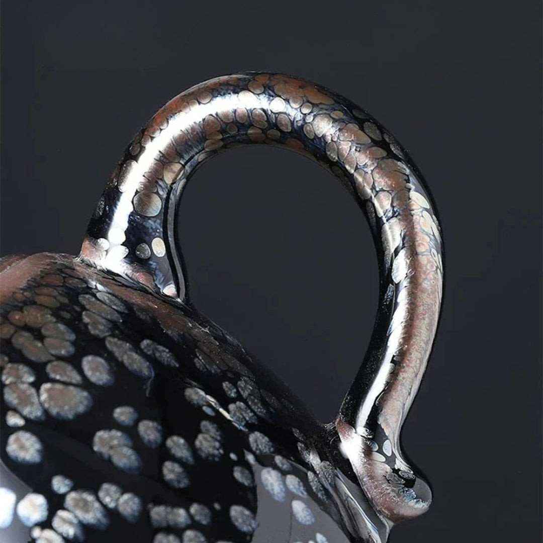 Détail de l’anse d’une théière japonaise à glaçure cristallisée, montrant les motifs minéraux argentés.