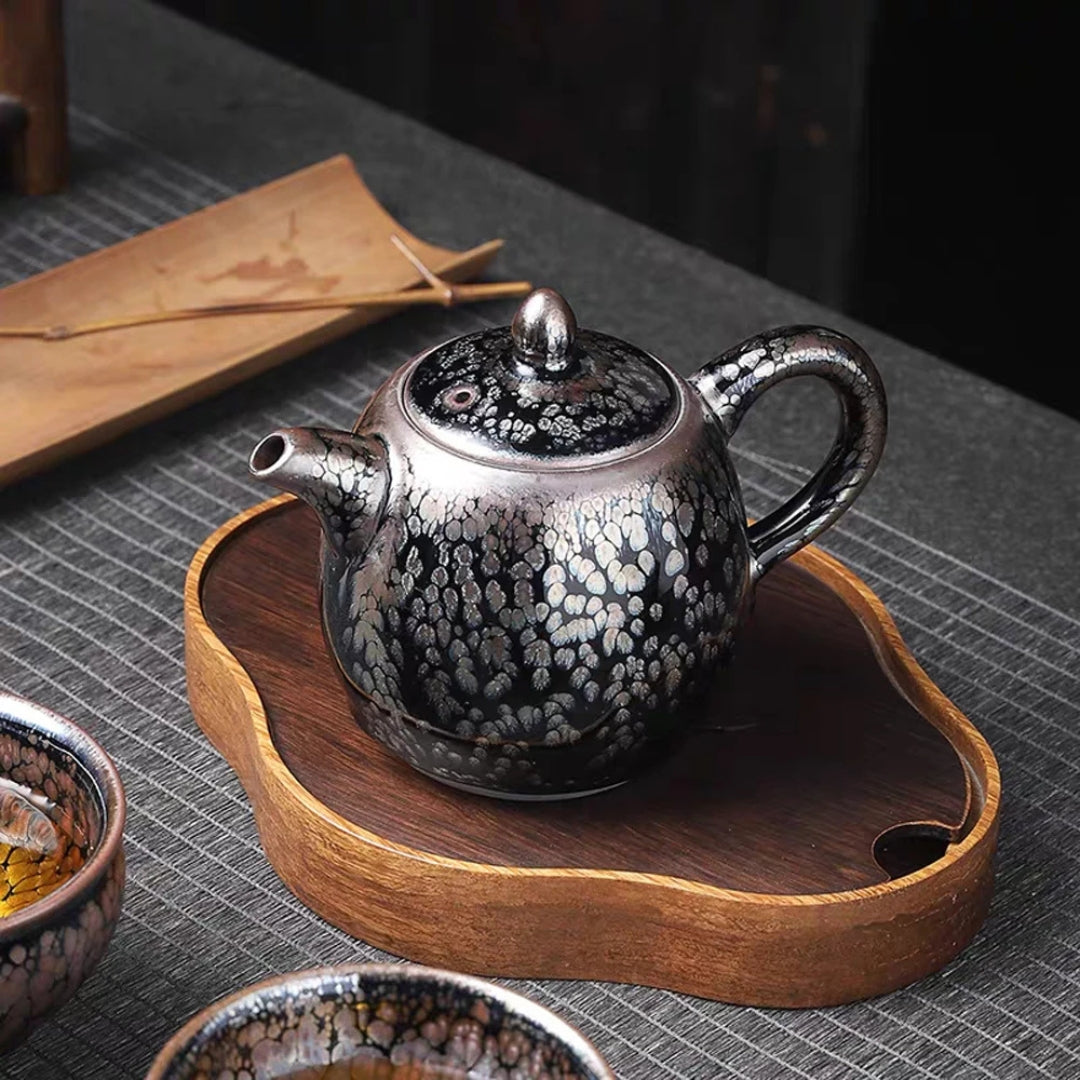Théière japonaise à glaçure cristallisée posée sur un plateau en bois, accompagnée de bols à thé assortis.